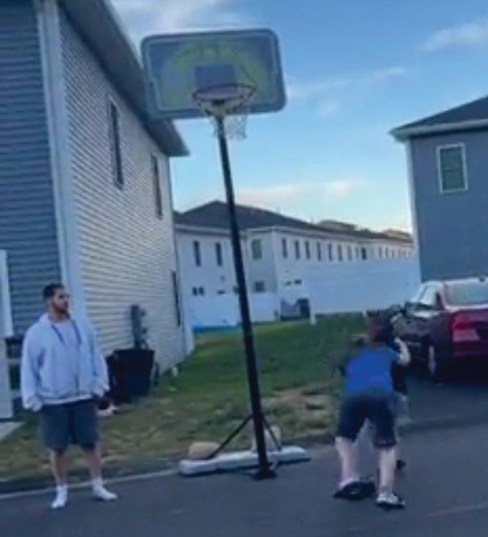 In the video, two children start fighting underneath a basketball hoop. Eventually, as one child gains the advantage, an adult male who was watching the fight (at left), jumps into the brawl and tackles one of the children, falling on the street. The video posted on social media ends immediately after. 